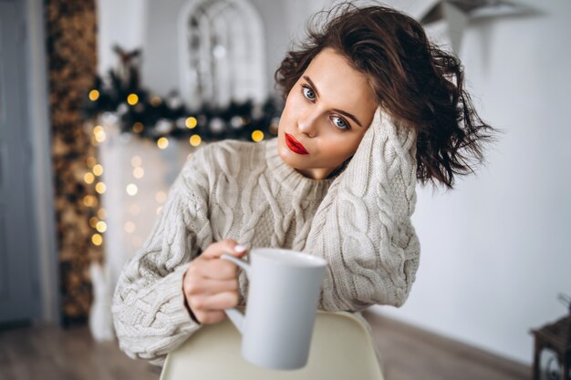 Pretty brunette in a warm sweater at home