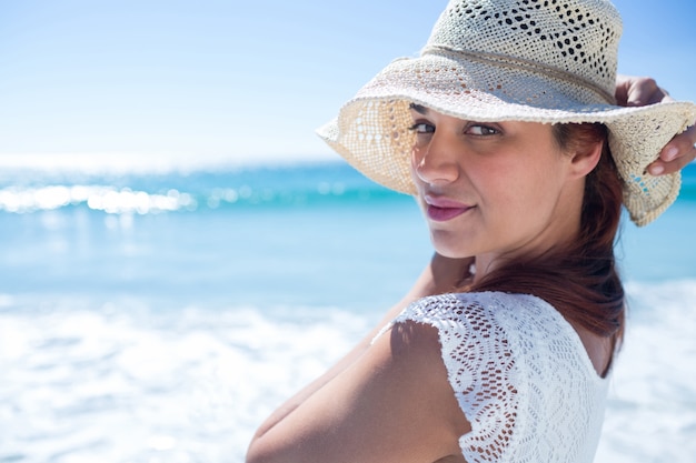 Pretty brunette wearing straw hat and looking at camera