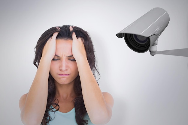 Pretty brunette with a headache against cctv camera