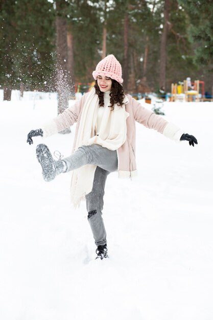 森で雪と遊ぶかなりブルネットの女性