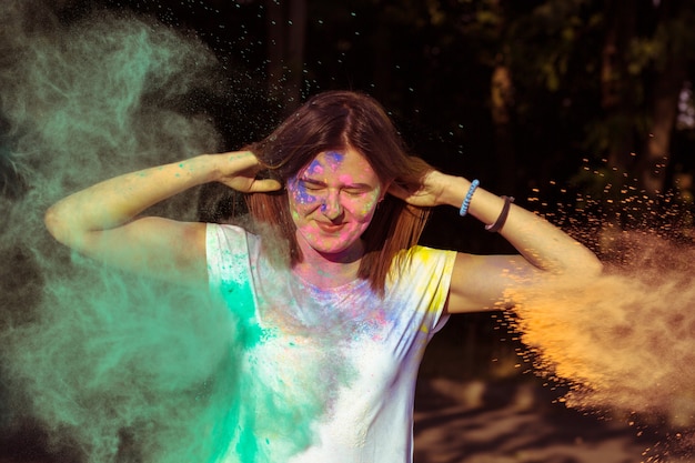 Pretty brunette woman with long hair covered with colorful Holi powder