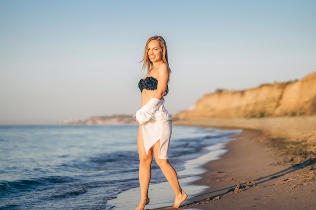 Pretty brunette woman with a white shirt posing on the beach