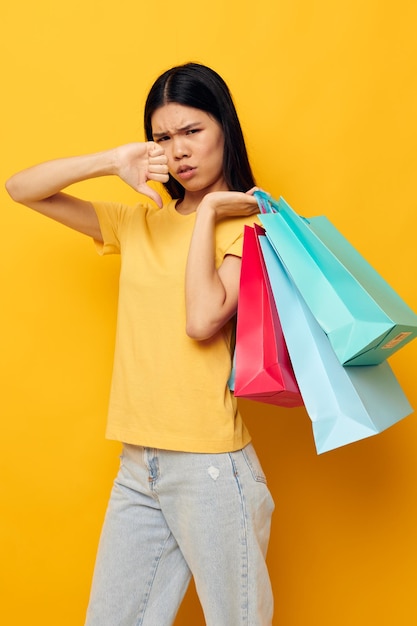 Pretty brunette in a yellow Tshirt with multicolored shopping bags studio model unaltered