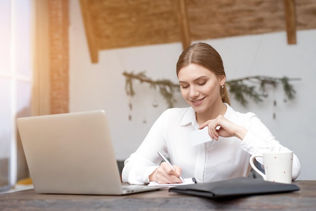 Photo pretty business woman working on computer and holding credit card in hand online shopping