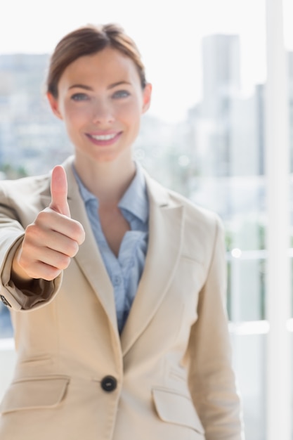 Pretty businesswoman giving thumb up to camera