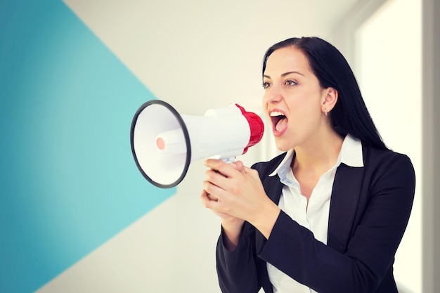 Pretty businesswoman shouting with megaphone against modern blue and white room
