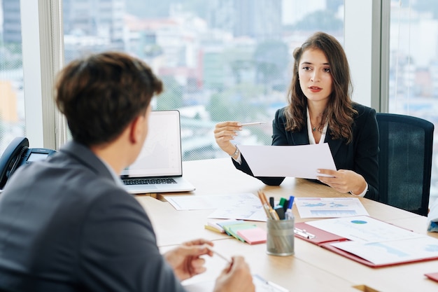 Pretty businesswoman talking to coworker