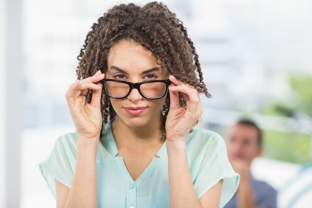 Pretty businesswoman tilting her reading glasses