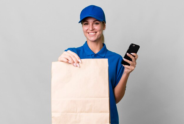 Pretty caucasian delivery woman with a paper bag and a phone