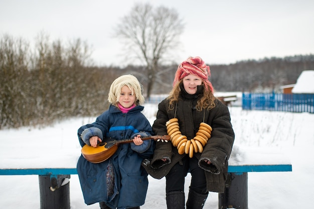 Pretty caucasian village sisters sit on the bench with balalaika