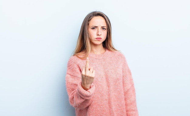 pretty caucasian woman feeling angry, annoyed, rebellious and aggressive, flipping the middle finger, fighting back