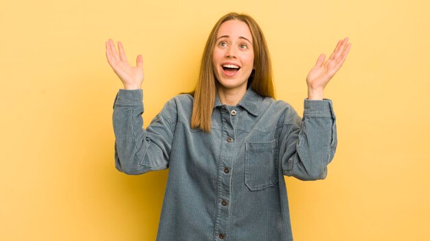 幸せを感じているかなり白人の女性は、空中で両手を上げて勝利を祝う幸運と驚きを驚かせました