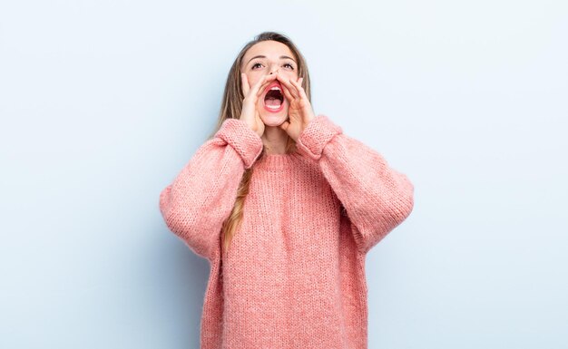 Pretty caucasian woman feeling happy, excited and positive, giving a big shout out with hands next to mouth, calling out