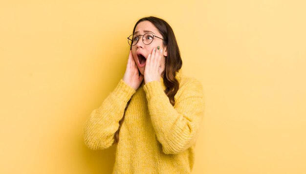 Pretty caucasian woman feeling happy excited and surprised looking to the side with both hands on face