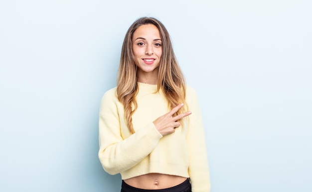 Pretty caucasian woman feeling happy, positive and successful, with hand making v shape over chest, showing victory or peace