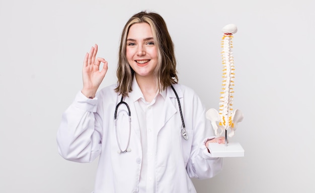 Pretty caucasian woman feeling happy showing approval with okay gesture spine specialist