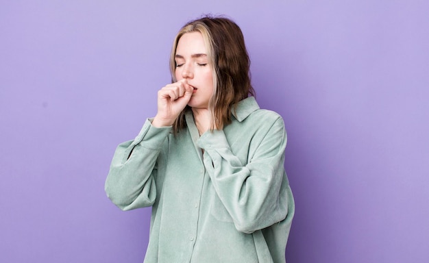 Foto donna abbastanza caucasica che si sente male con mal di gola e sintomi influenzali che tosse con la bocca coperta