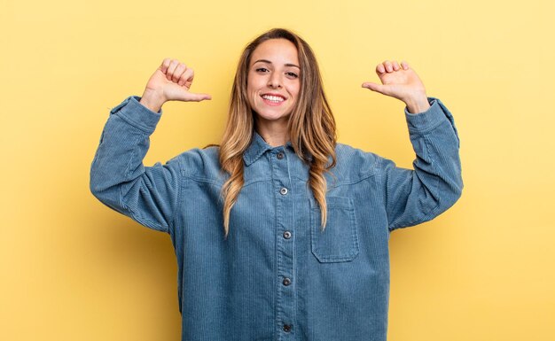 Pretty caucasian woman feeling proud, arrogant and confident, looking satisfied and successful, pointing to self