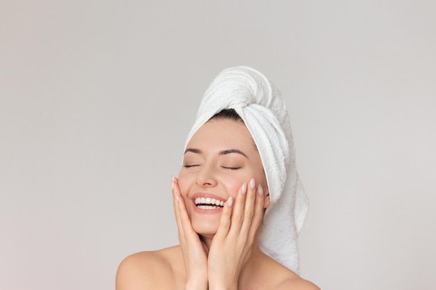 pretty caucasian woman laughs closes her eyes and gently touches her face with her hands