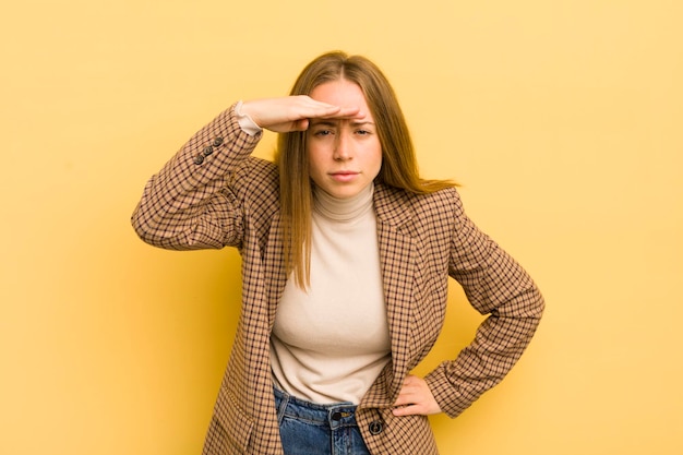 Pretty caucasian woman looking bewildered and astonished with hand over forehead looking far away watching or searching