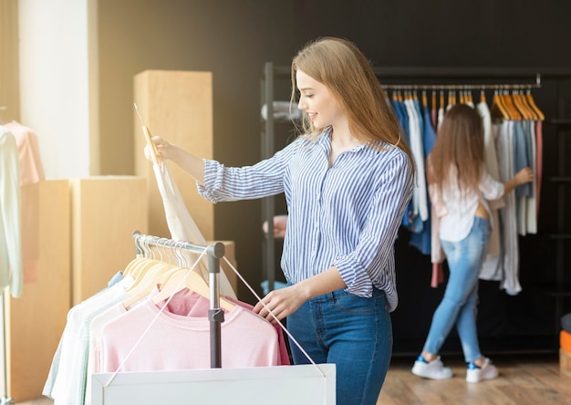 Pretty Caucasian Woman Looking At Blouse And Smiling, shopping time