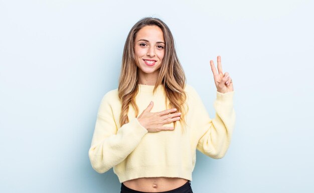 Donna abbastanza caucasica che sembra felice, sicura e degna di fiducia, sorride e mostra il segno della vittoria, con un atteggiamento positivo