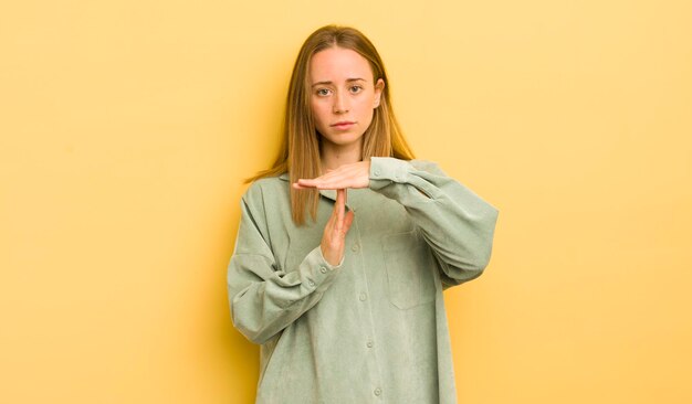 Pretty caucasian woman looking serious stern angry and displeased making time out sign