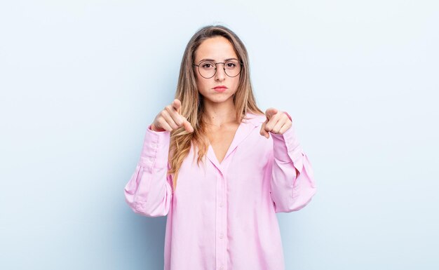 Pretty caucasian woman pointing forward at camera with both fingers and angry expression, telling you to do your duty