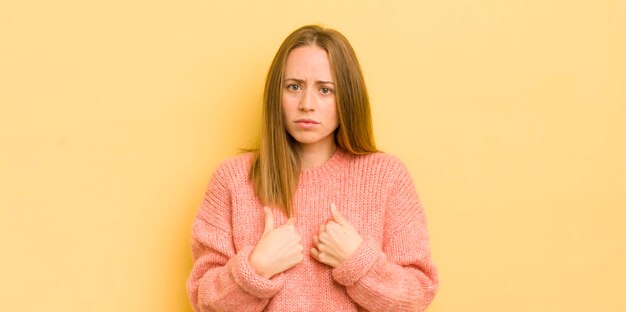 写真 混乱した奇妙な表情で自分を指しているかなり白人の女性は、選ばれたことにショックを受けて驚いた