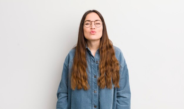 Photo pretty caucasian woman pressing lips together with a cute fun happy lovely expression sending a kiss