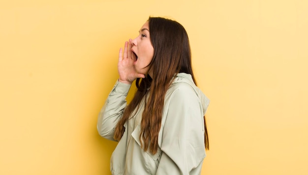 Vista del profilo della donna abbastanza caucasica che sembra felice ed eccitata che grida e chiama per copiare lo spazio sul lato