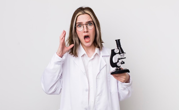 Pretty caucasian woman screaming with hands up in the air scientist with microscope concept