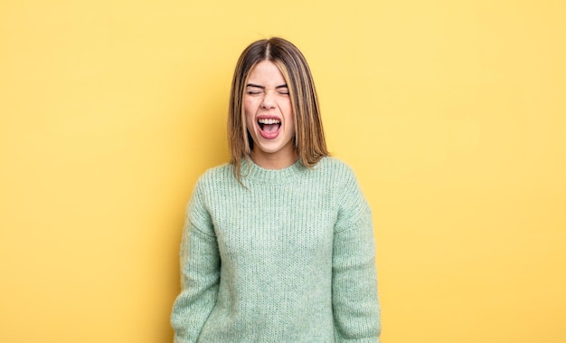 Pretty caucasian woman shouting aggressively, looking very angry, frustrated, outraged or annoyed, screaming no