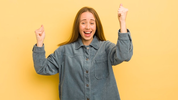 Pretty caucasian woman shouting triumphantly looking like\
excited happy and surprised winner celebrating