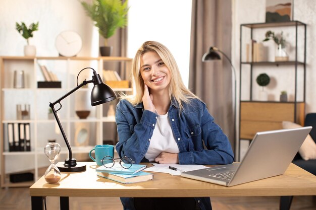 Pretty Caucasian woman sitting at desk with laptop indoors and smiling