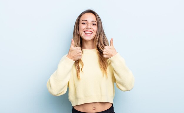 Foto donna abbastanza caucasica che sorride ampiamente e sembra felice, positiva, sicura di sé e di successo, con entrambi i pollici in su