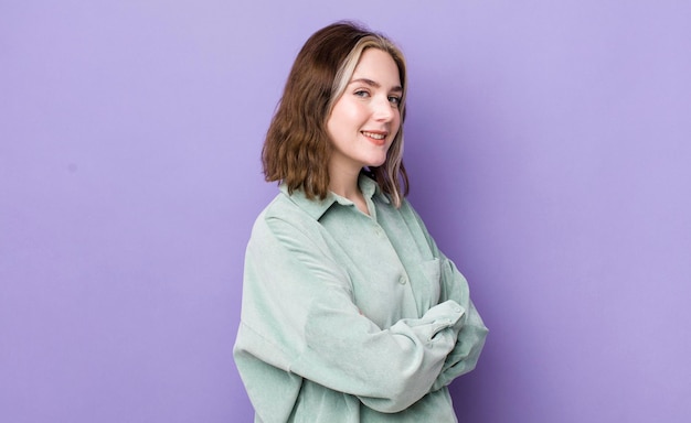 Pretty caucasian woman smiling to camera with crossed arms and a happy confident satisfied expression lateral view