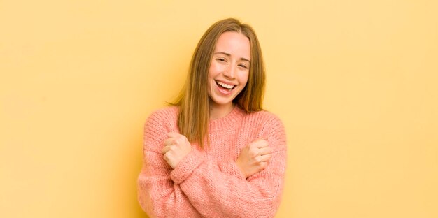 Pretty caucasian woman smiling cheerfully and celebrating with fists clenched and arms crossed feeling happy and positive