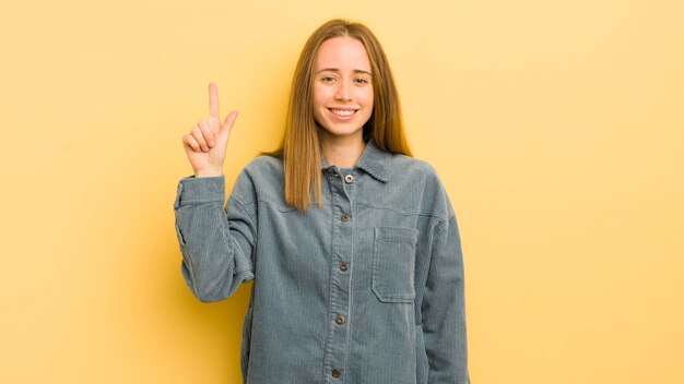 スペースをコピーするために片手で元気にそして幸せに上向きに笑っているかなり白人女性