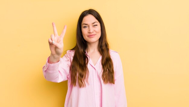 Pretty caucasian woman smiling and looking friendly showing number two or second with hand forward counting down