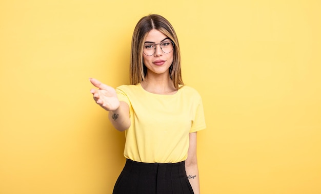 pretty caucasian woman smiling, looking happy, confident and friendly, offering a handshake to close a deal, cooperating