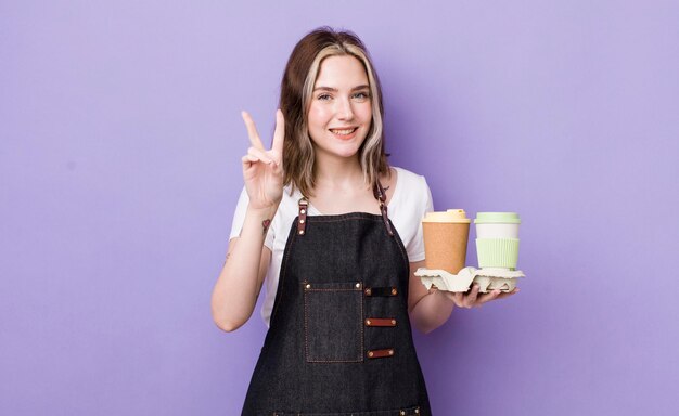 Pretty caucasian woman smiling and looking happy gesturing victory or peace take away coffee concept