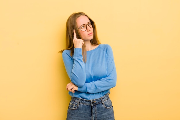 Pretty caucasian woman with a concentrated look wondering with a doubtful expression looking up and to the side