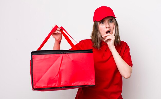 Pretty caucasian woman with mouth and eyes wide open and hand on chin pizza delivery concept