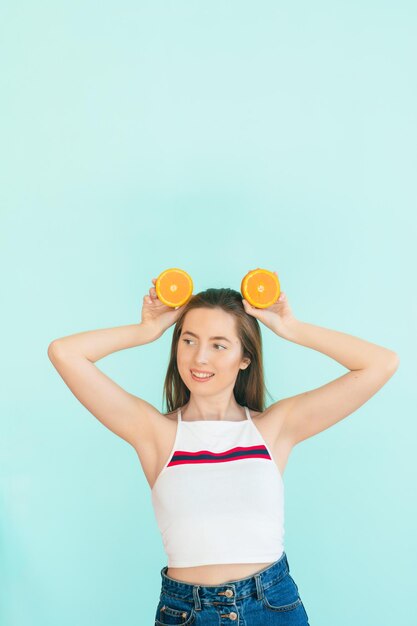 Pretty charming cheerful funny natural pure girl having two pieces of orange