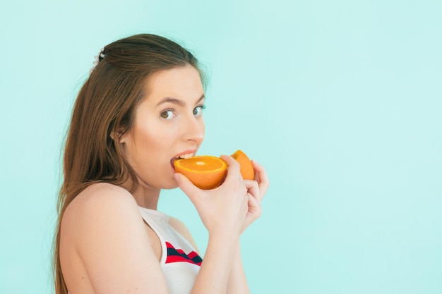 Pretty charming cheerful funny natural pure girl having two pieces of orange