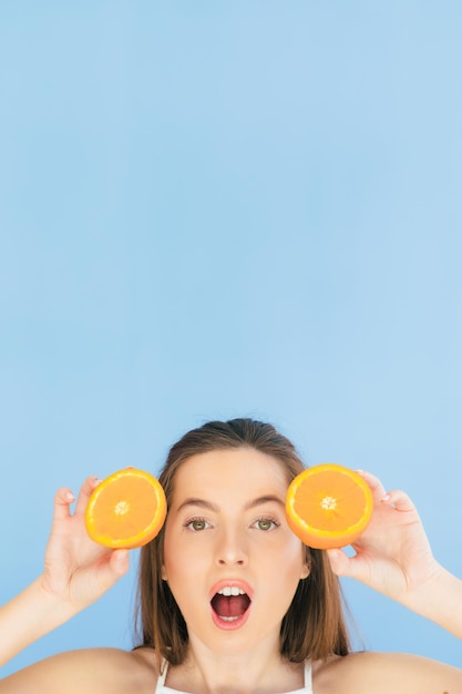 Pretty charming cheerful funny natural pure girl having two pieces of orange