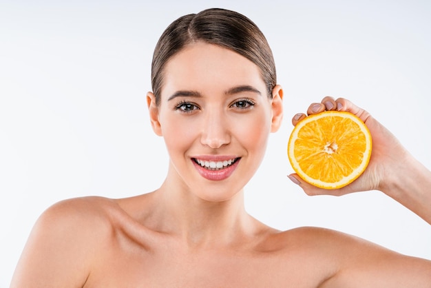 Pretty cheerful nude natural girl showing piece of orange isolated on white background