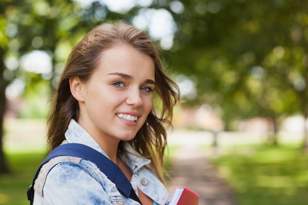 Pretty cheerful student holding folder and notebook