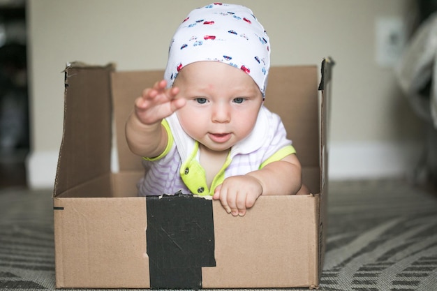 Photo pretty child baby boy sitting inside a box